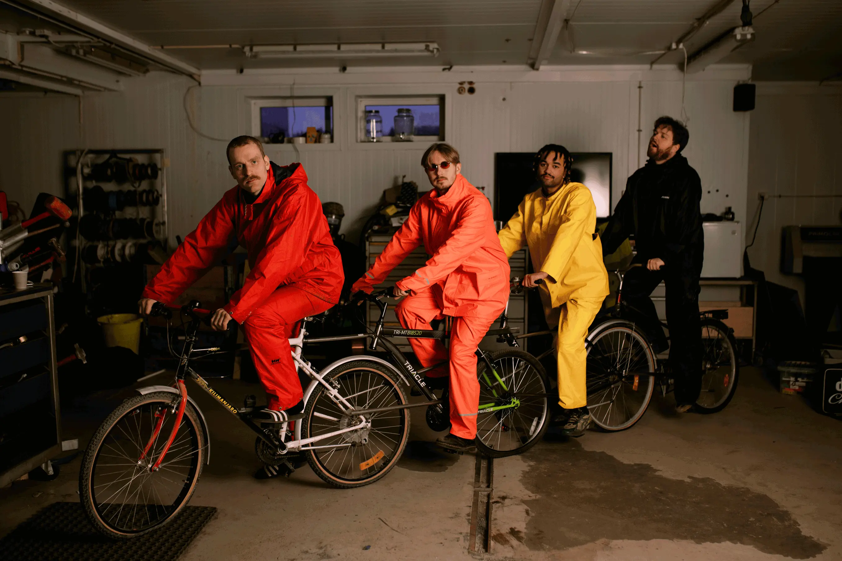 Tøfl band members sitting on a bicycle in a garage.