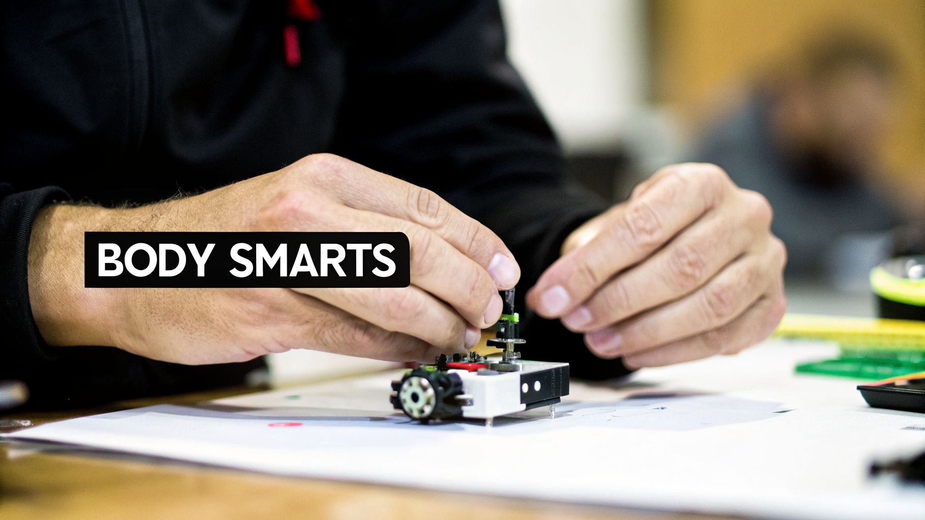 Close-up of hands assembling a small robot, illustrating body smarts or kinesthetic intelligence.