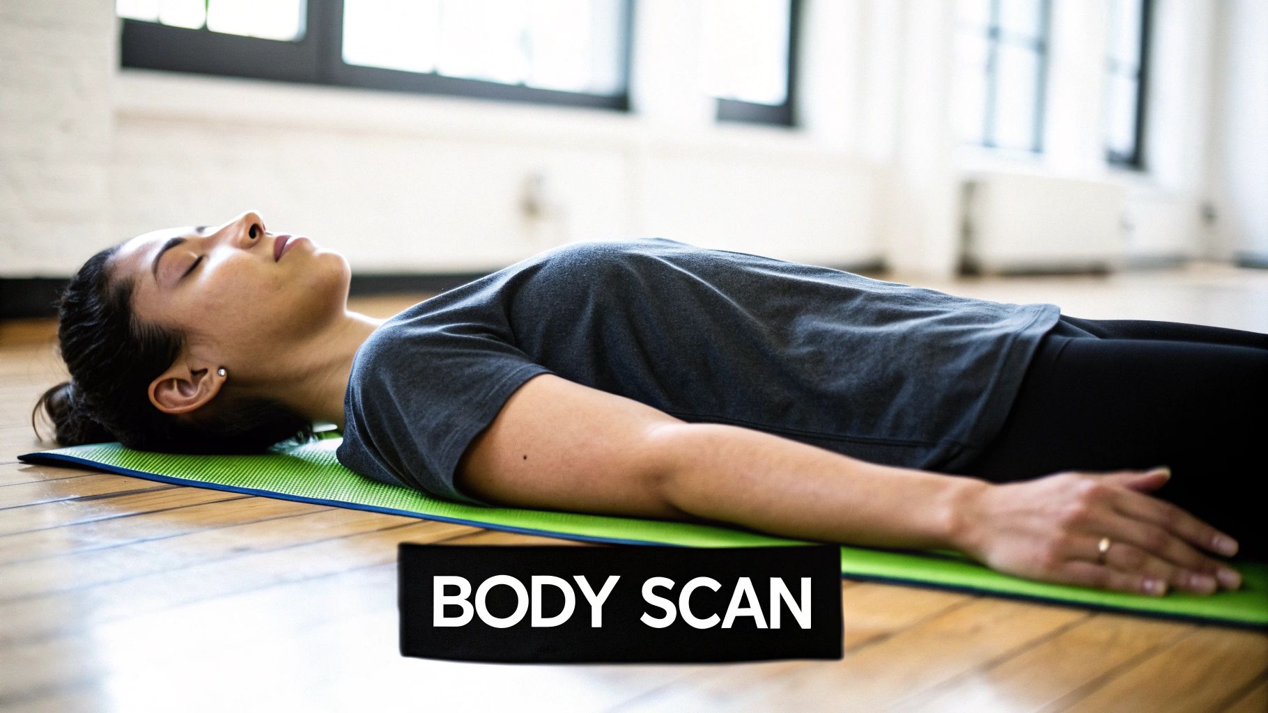 A woman lies relaxed on a green yoga mat with eyes closed, practicing a body scan meditation.