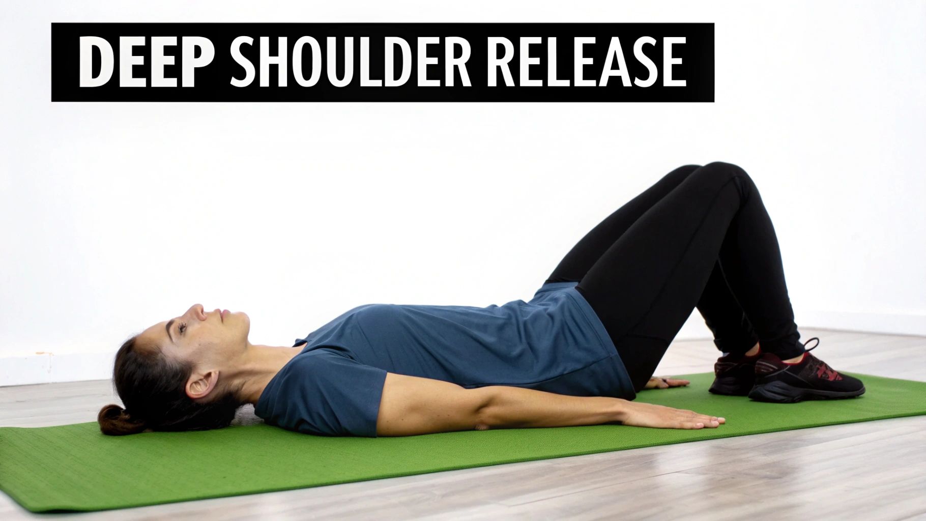 A woman lies on a green yoga mat with bent knees, demonstrating a deep shoulder release yoga pose.