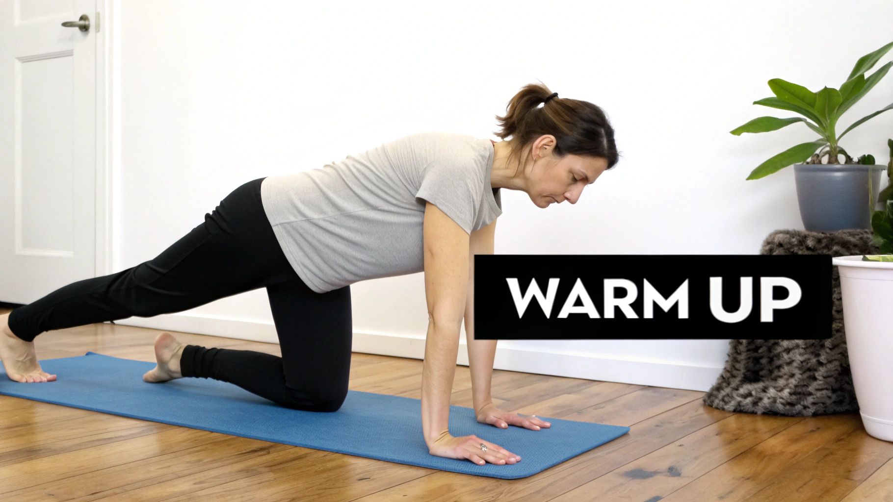 A woman on a blue yoga mat demonstrating a plank variation as part of a warm-up exercise.