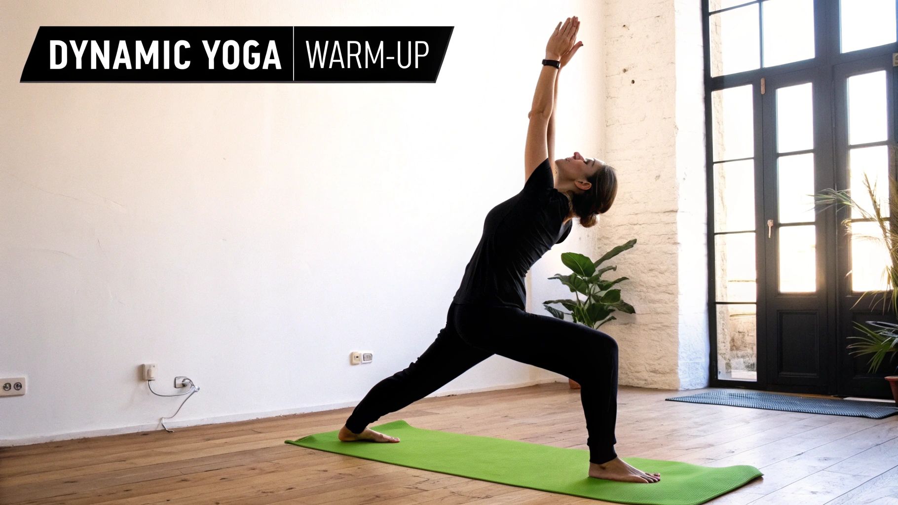 A woman in black activewear performs a dynamic yoga warm-up pose on a green mat indoors.