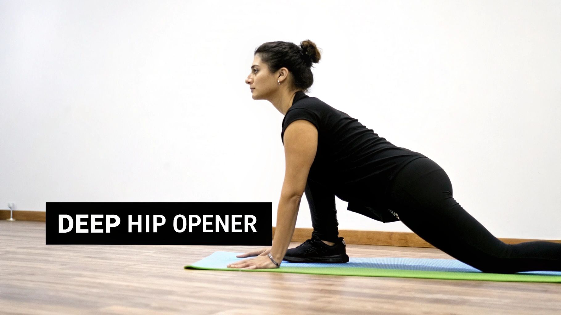 A woman performs a deep hip opener stretch on a yoga mat, showcasing flexibility and mobility.