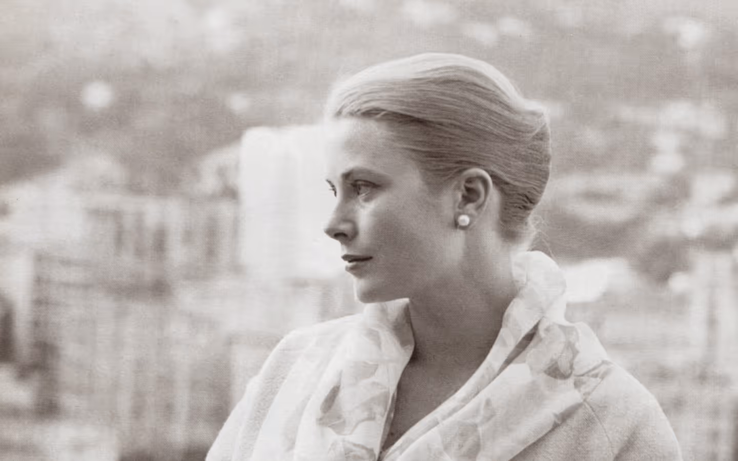 Black and white side profile portrait of a woman with her hair styled in an elegant updo, wearing pearl earrings and a patterned scarf.