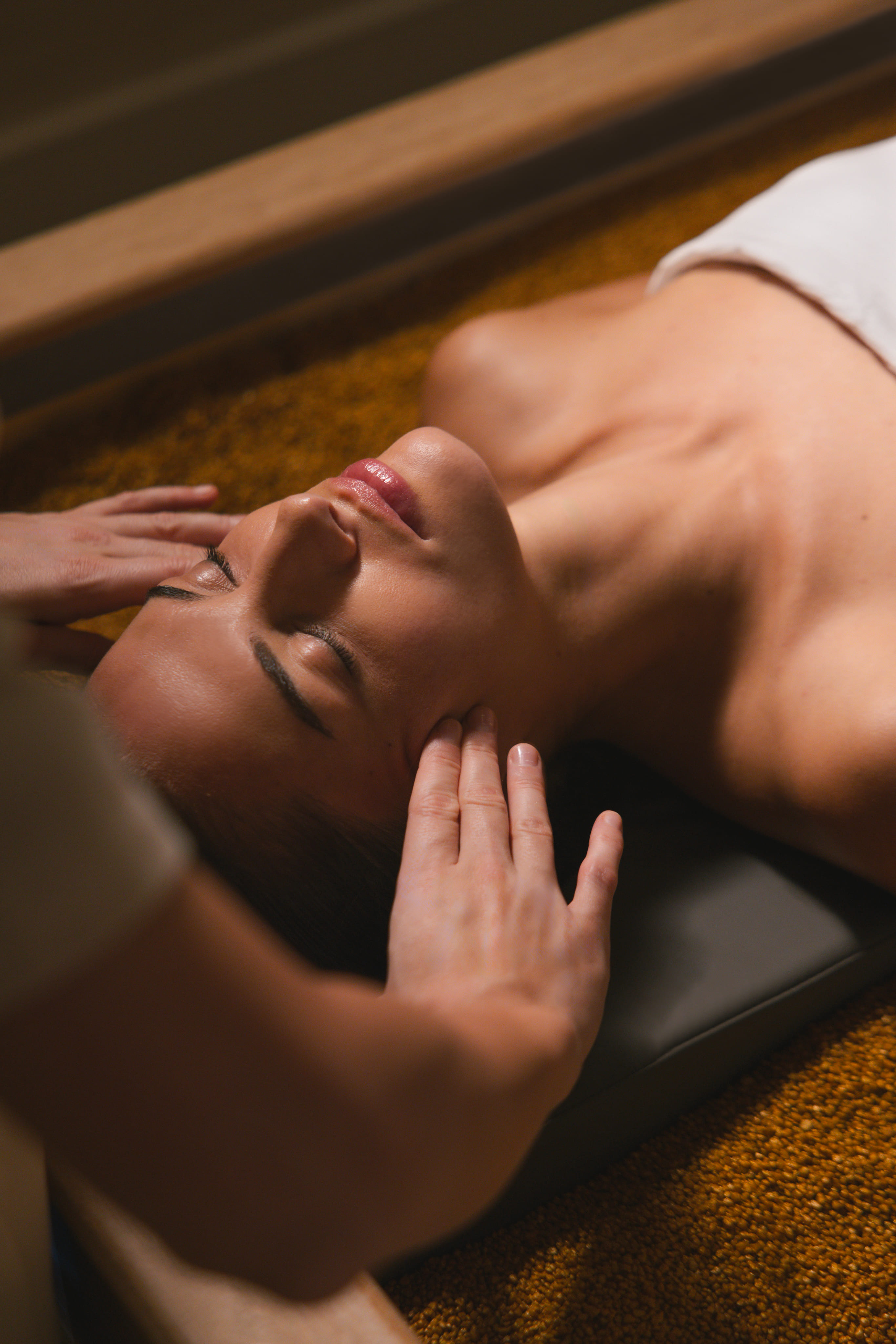 Woman receiving a relaxing head massage while lying down with eyes closed.