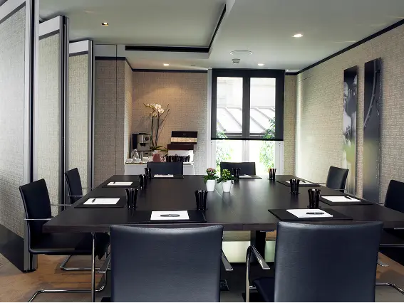 Modern conference room with a large dark table, black leather chairs, and neatly arranged notepads and pens.