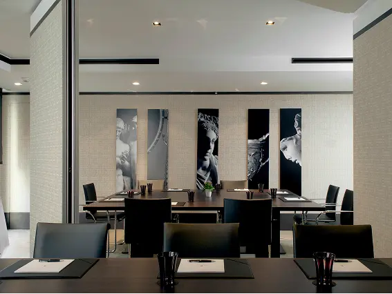 Modern conference room with black chairs and tables, featuring five black and white artistic wall panels.