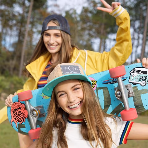 Teen girls in hats with skateboards in a park