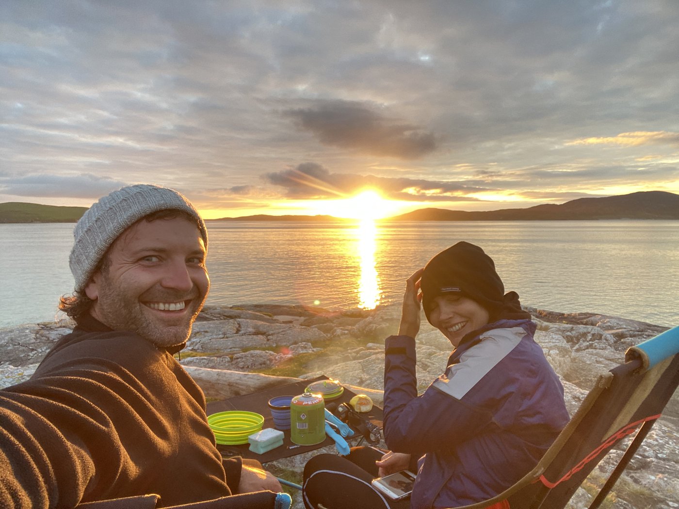 Two travellers at a lochside camp at sunset in the Scottish islands