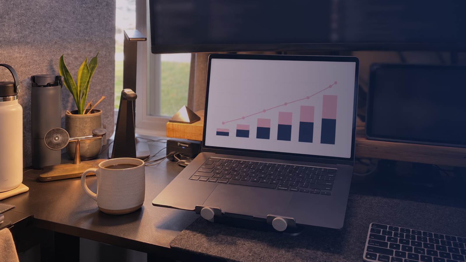 A laptop on a desk showing a simple two-bar chart, ready for a budget meeting with finance