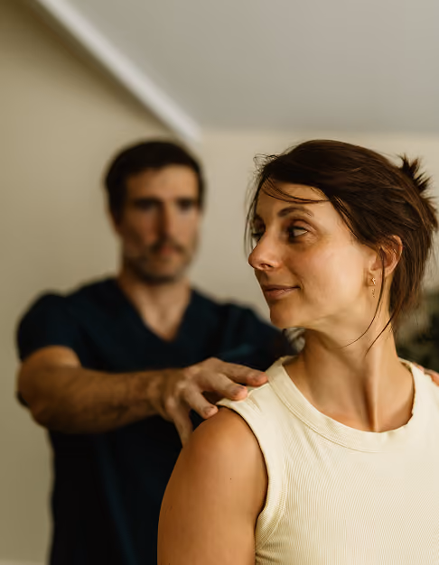 A therapist gently placing hands on a woman's shoulders during a session.