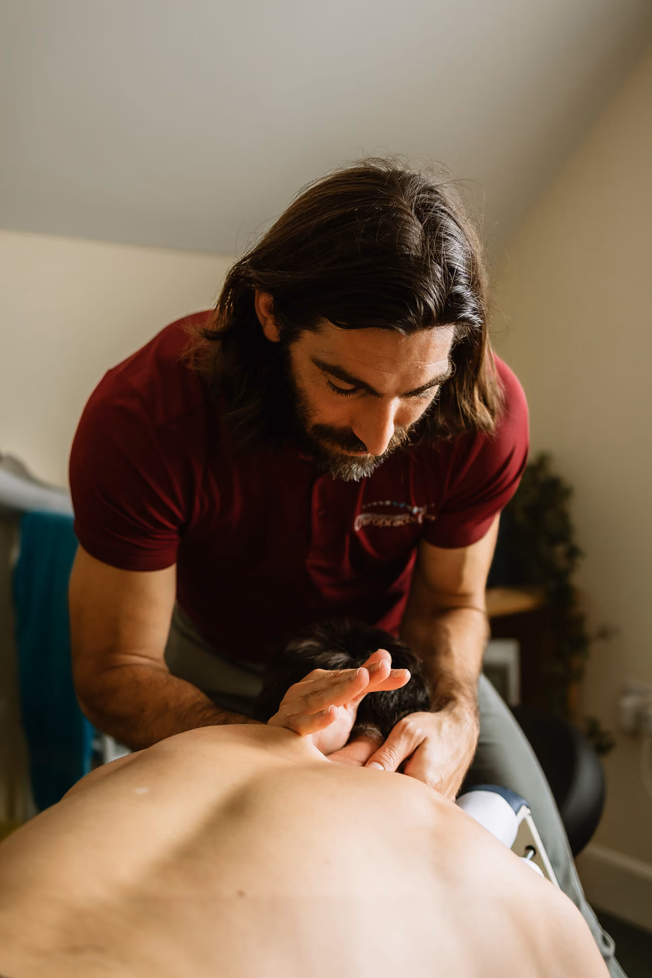 Chiropractor performing neck adjustment on a client lying face down on a massage table.
