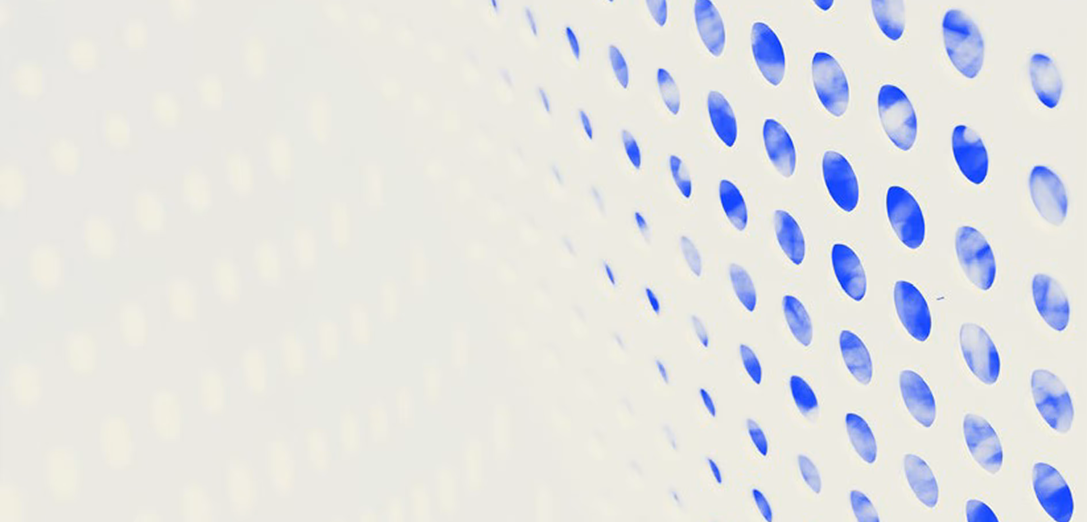 Curved white surface with evenly spaced oval cutouts showing blue sky with clouds behind.