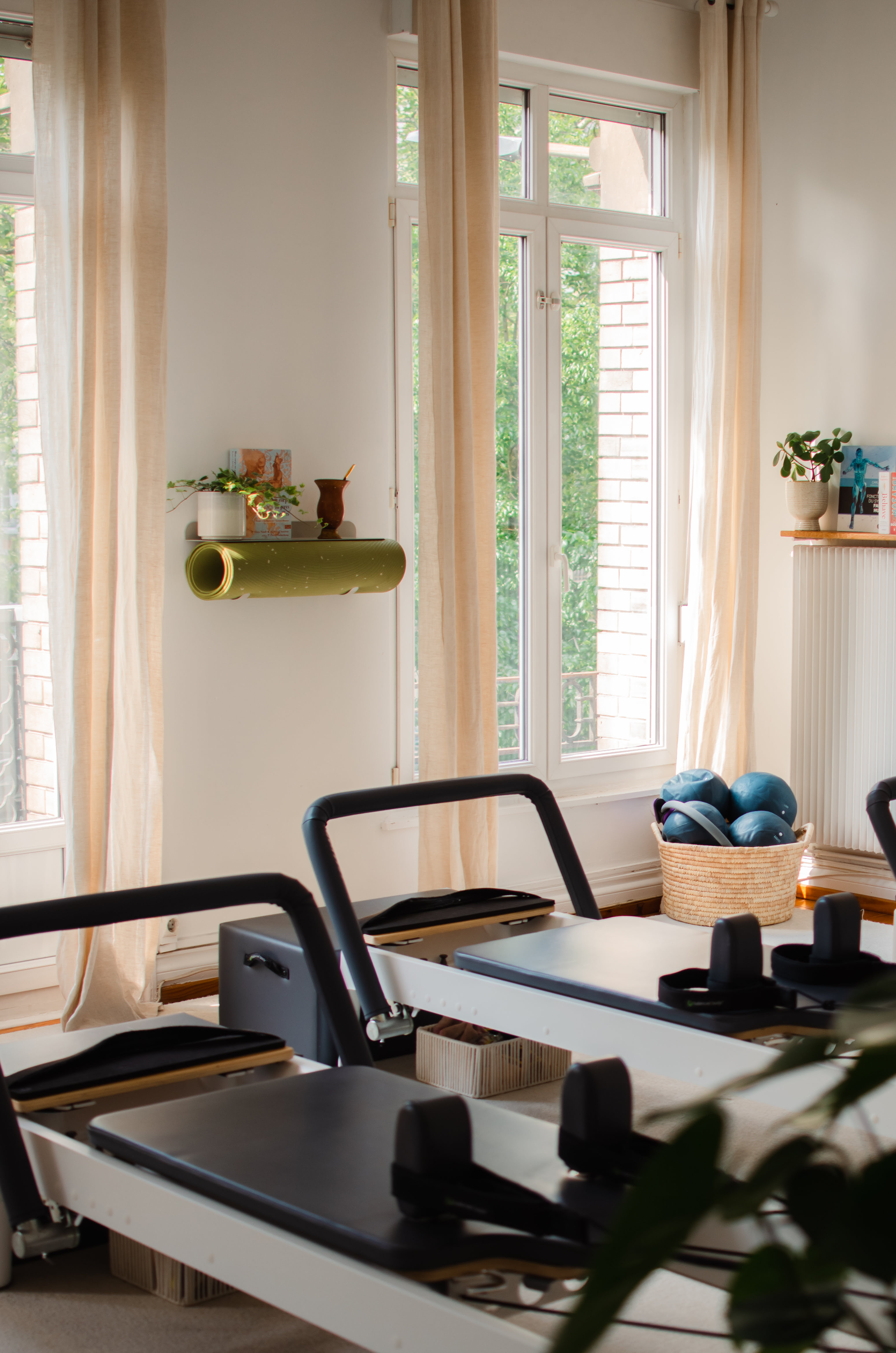 Reformers alignés dans le studio Healthilona, ballons lestés et tapis de Pilates, ambiance chaleureuse et lumineuse