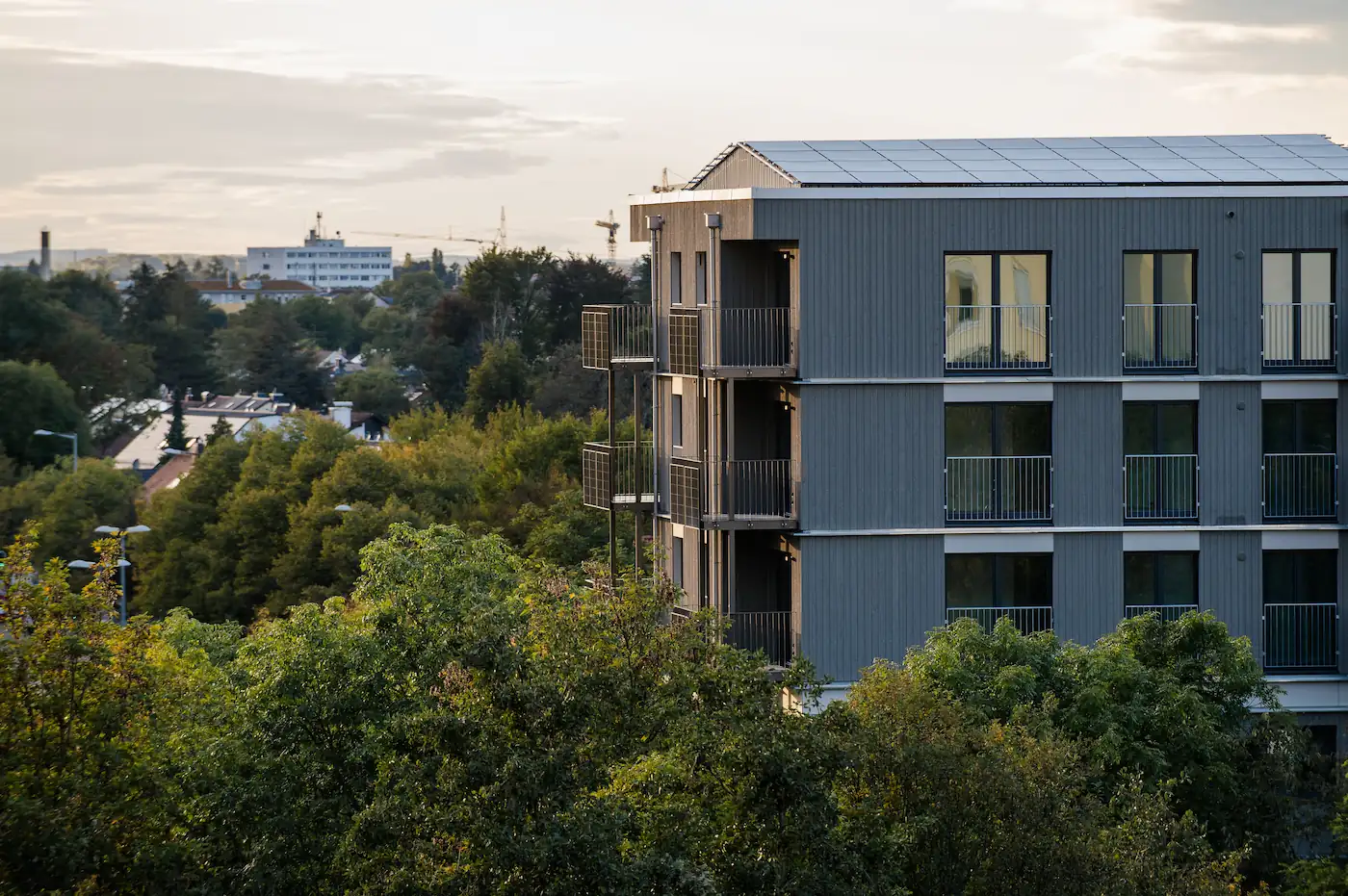 Seriell saniertes Mehrfamilienhaus mit dunkler Metallfassade und neuen Balkonen