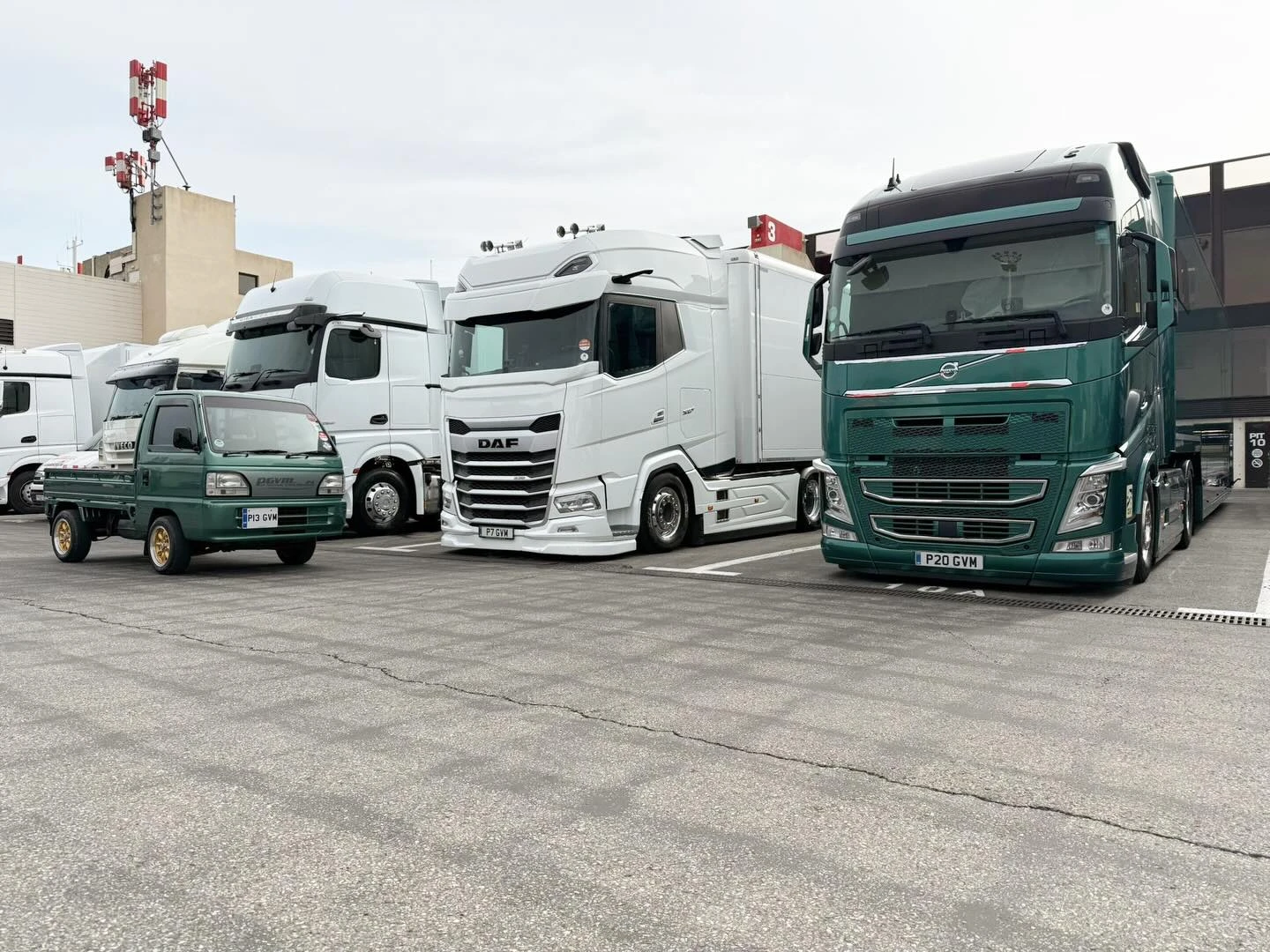 Front view of two vintage Formula 1 race cars, with the white Brabham car at the front and a silver and red car behind it, loaded inside a transport trailer.