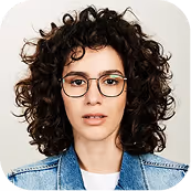 Woman with curly dark hair wearing glasses and a blue denim jacket on white background.