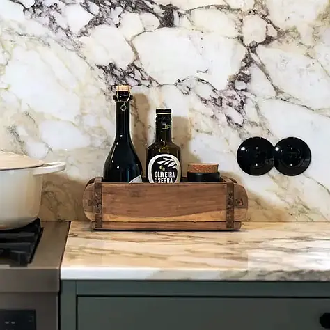 Houten houder met twee olieflessen en een kurk op marmeren keukenblad.