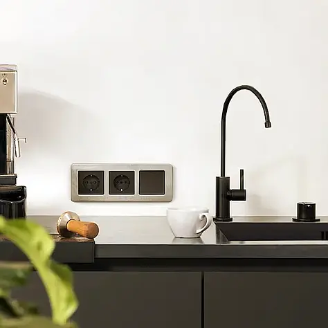 Moderne zwarte keuken met een zwarte kraan, espressoapparaat, wit koffiekopje en een houten tamper op het aanrecht.