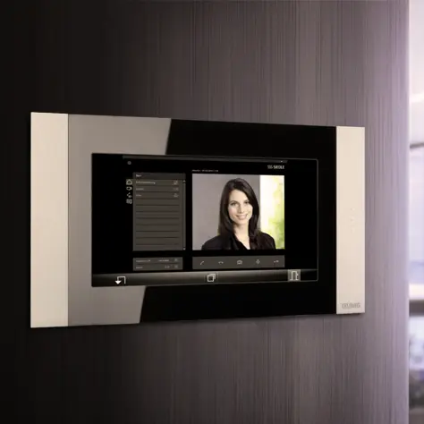 Modern video-intercom aan de muur met scherm waarop het portret van een vrouw wordt weergegeven.