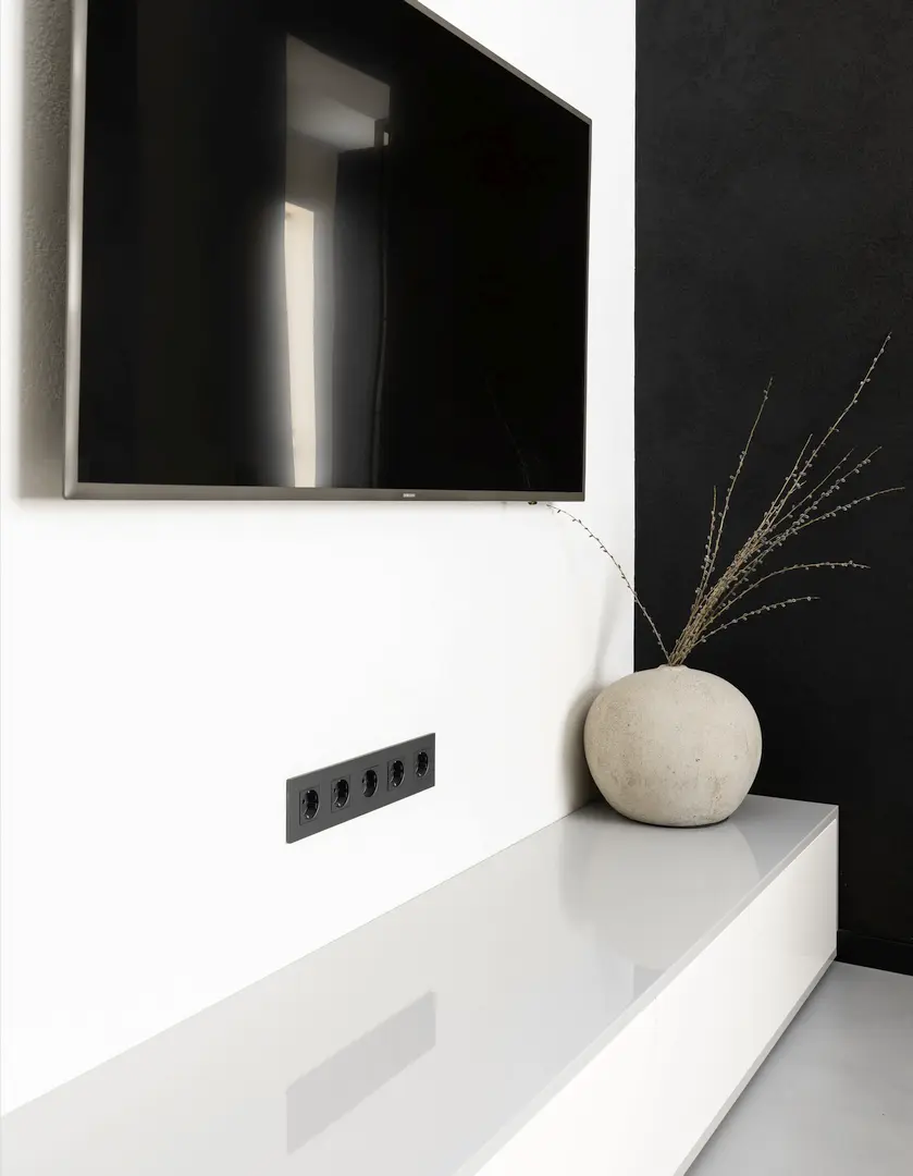 Detail van een minimalistisch interieur met tv en vijfvoudig stopcontact