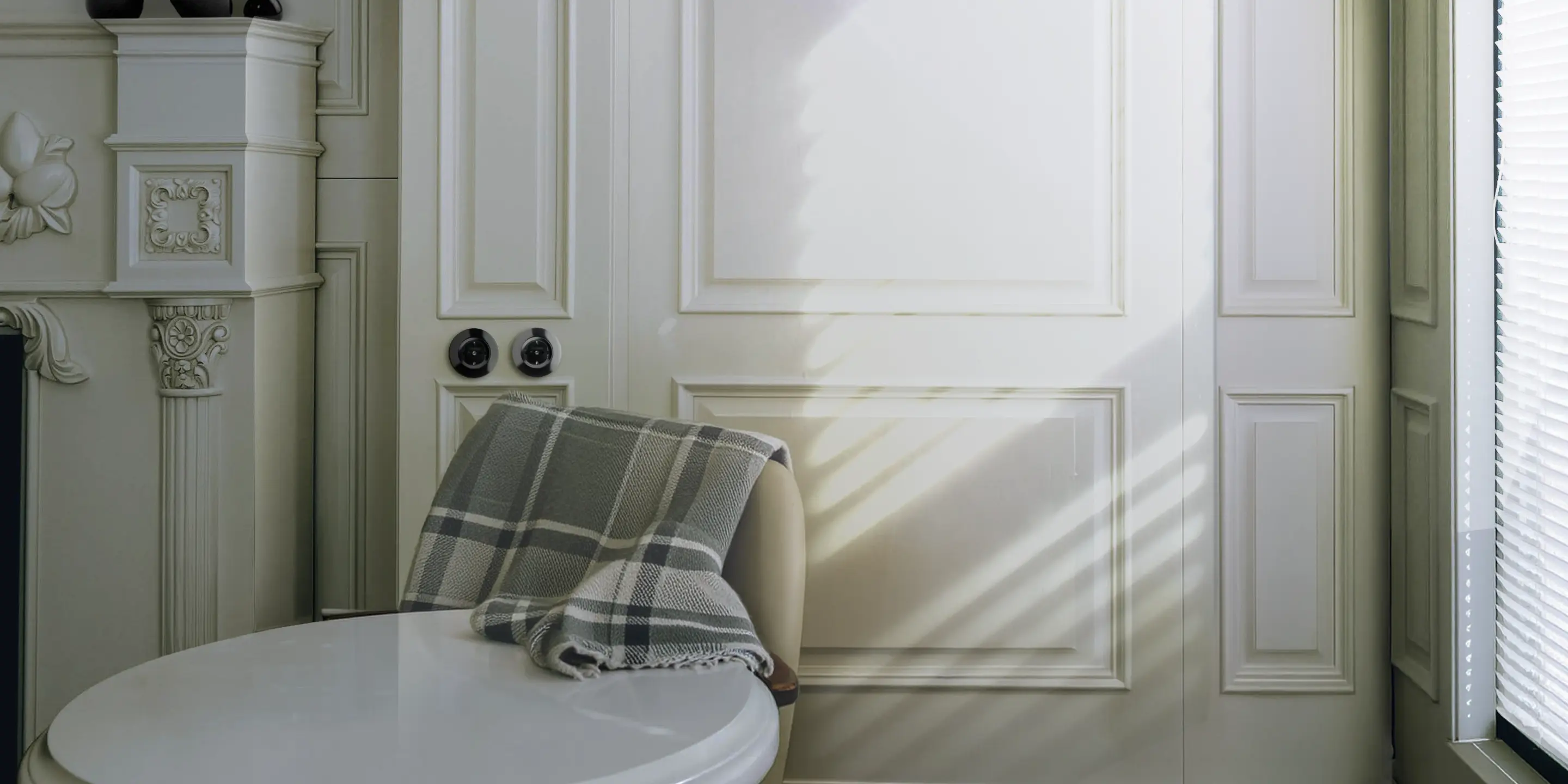 Zonnig interieur van een herenhuis met witte lambrisering en zwarte draaischakelaars op de wand