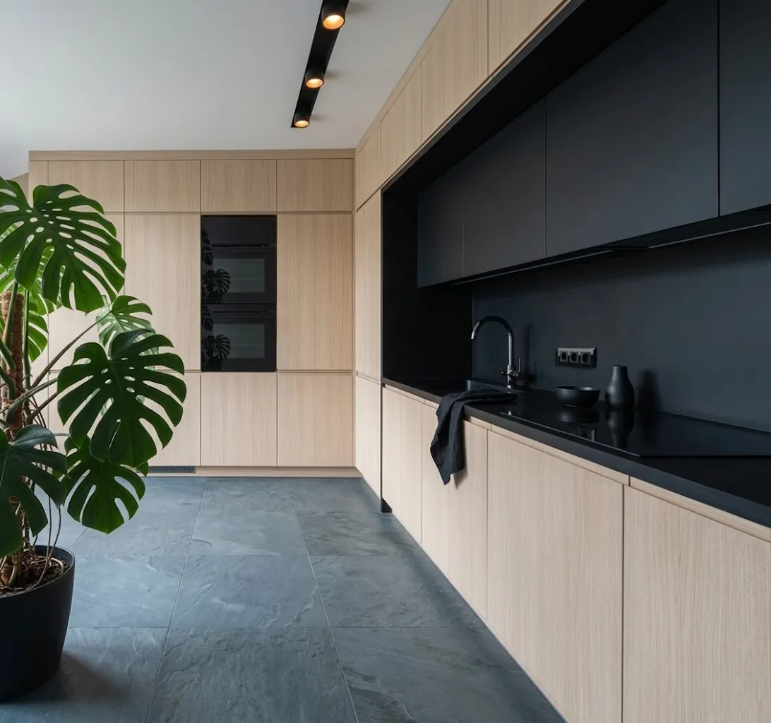 Overzicht van een lichte houtlook keuken met matzwarte werknis en zwart-glazen stopcontacten