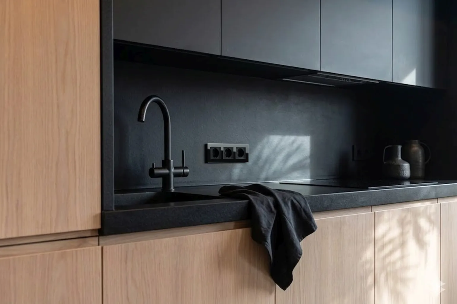 detail van stijlvolle keuken met zwarte werknis en zwarte glazen stopcontacten