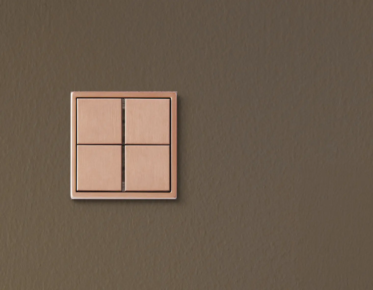 een Gira Ls 990 KNX schakelaar uitgevoerd in de kleur geborsteld brons, gemonteerd op een donkere olijfkleurige wand