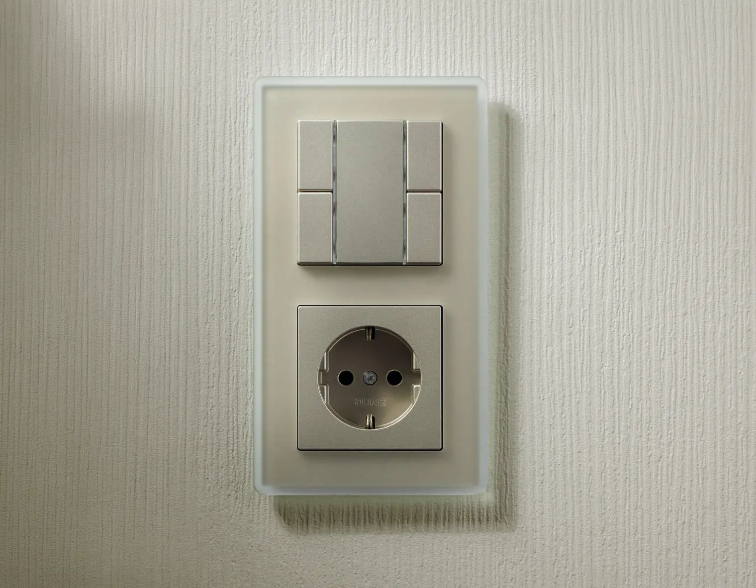 Een Gira A-Viva combinatie in de kleur champagne met een matglas afdekraam op een licht wand