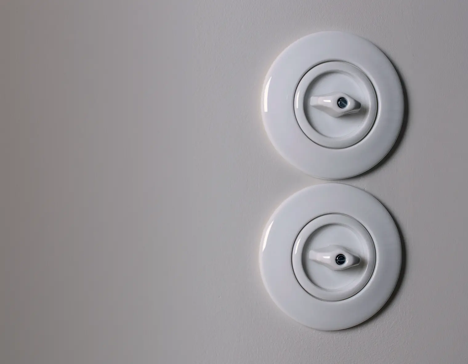 2 stuks Hager-Berker 1930 draaischakelaars uitgevoerd in wit porselein en gemonteerd op een lichtgrijze wand