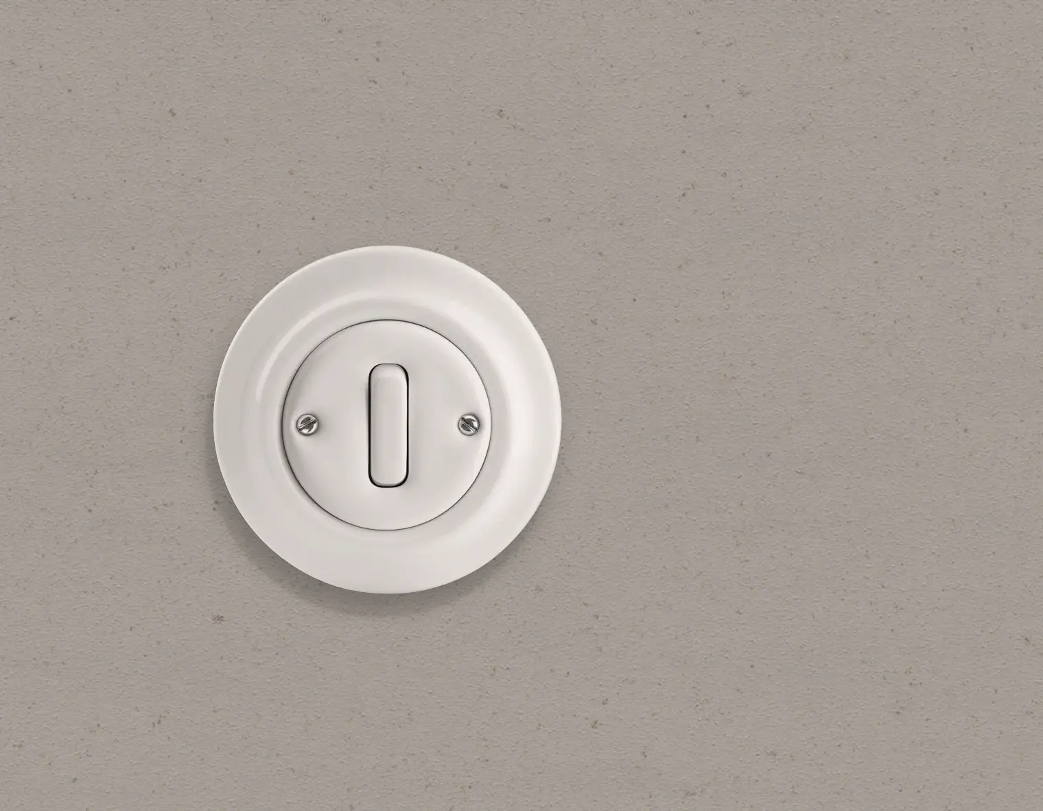 Een neutraal grijze wand met een witte Busch-Jaeger Decento retro-schakelaar van porselein