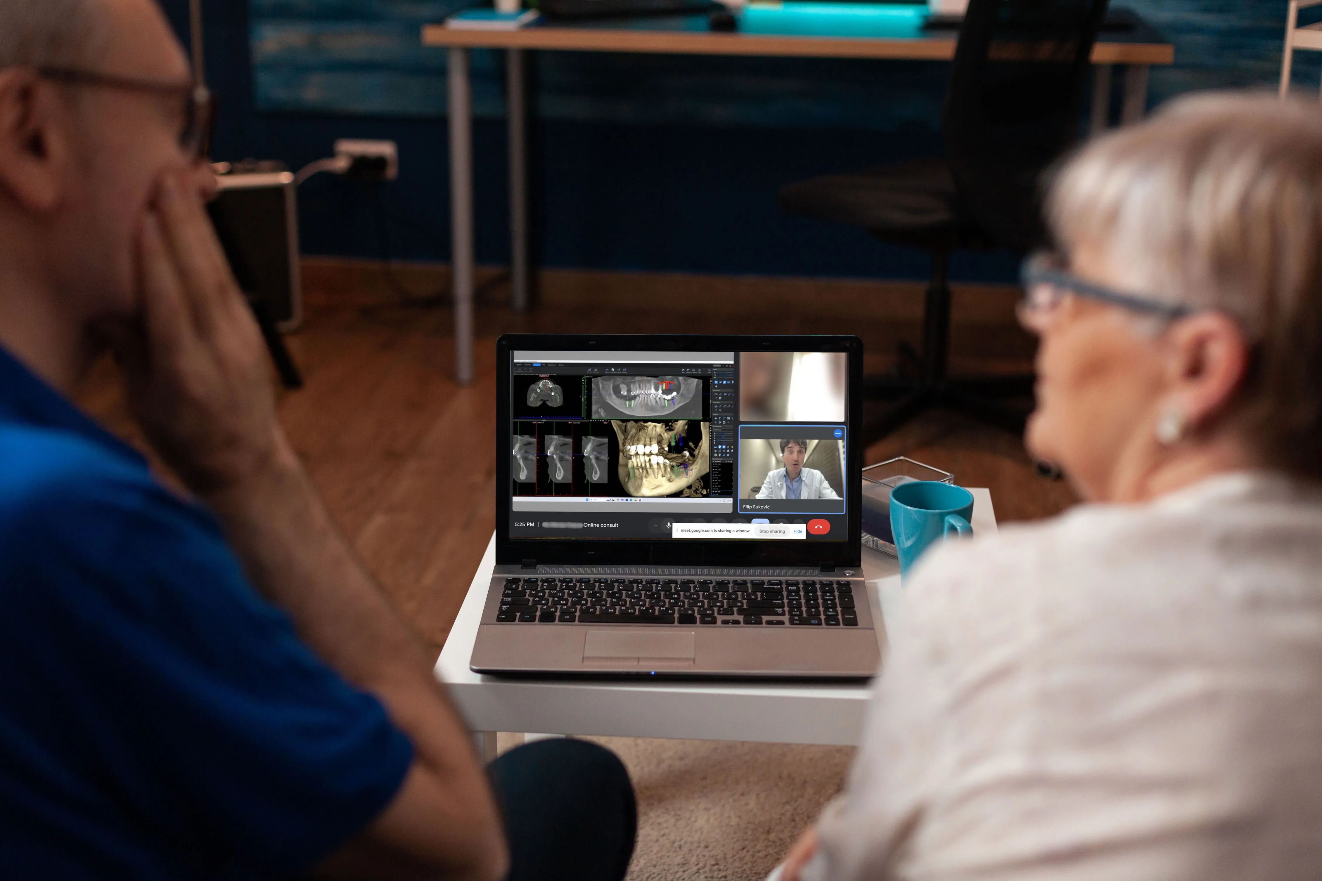Elderly couple having an online video consultation with a dentist showing dental x-rays on a laptop screen.