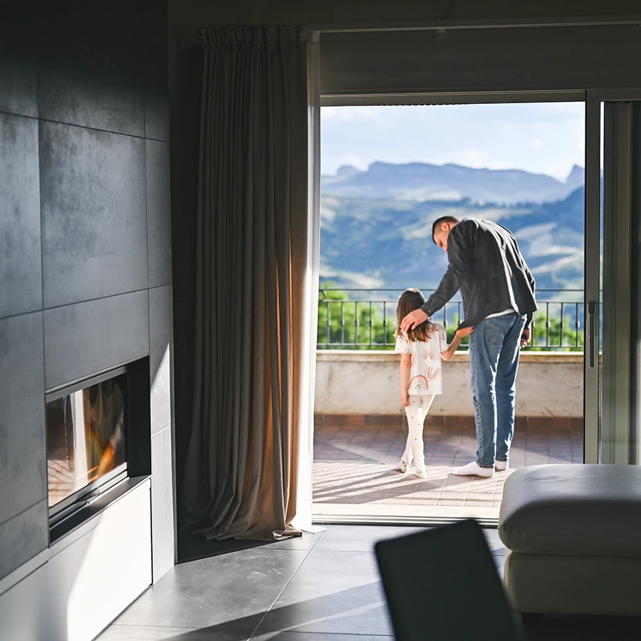 Man gently touching shoulder of young girl as they stand on balcony with mountain view.