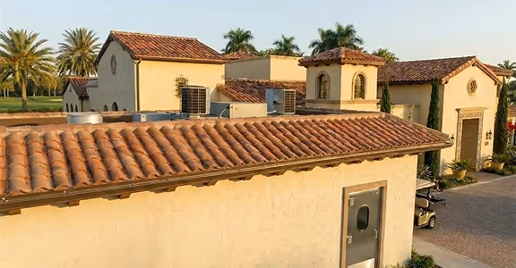 Mediterranean-style kitchen building with terracotta roof tiles, palm trees, and a golf cart nearby.