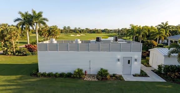 White full service kitchen with HVAC units on the roof in a tropical golf course setting with palm trees.