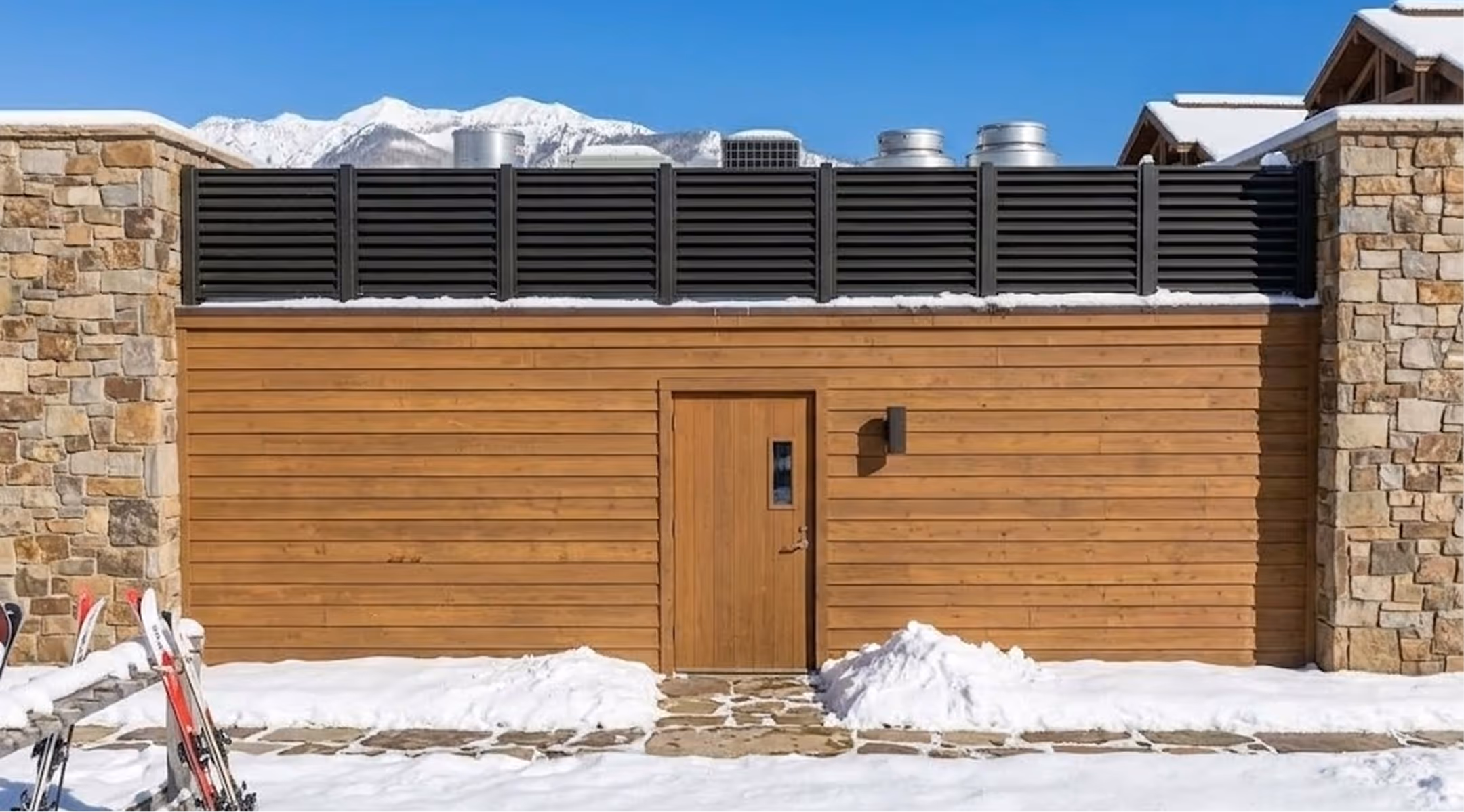 Snow-covered stone and wood full service kitchen with skis and snowy mountains in the background.
