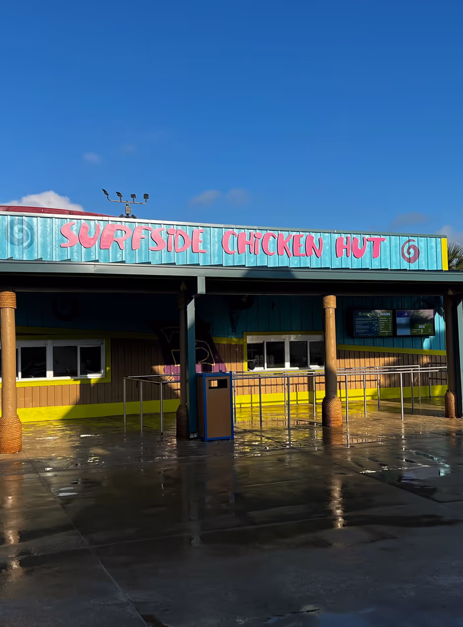 Empty outdoor quick-service restaurant called Surfside Chicken Hut under clear blue sky.