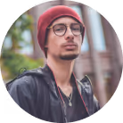 Mountain guide wearing a jacket and hat, looking confident with mountains in the background.