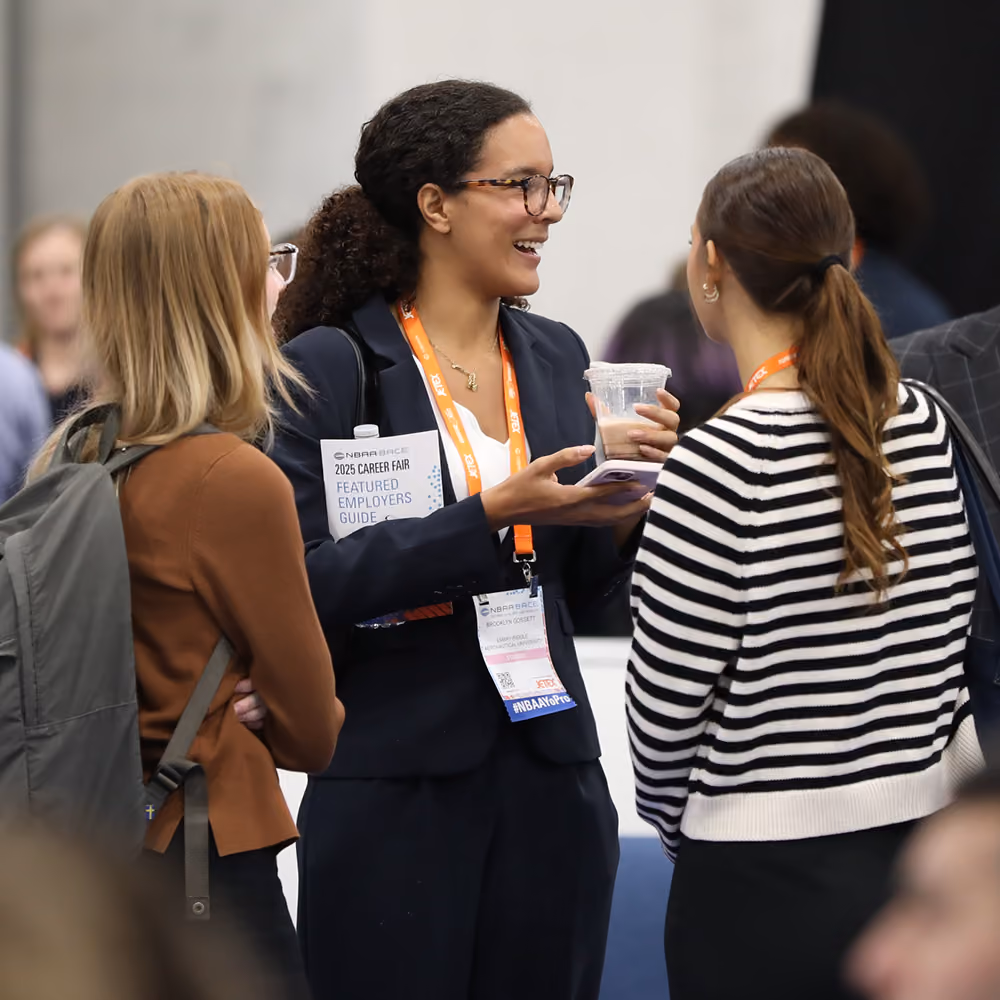 Three young women engaged in conversation at the 2025 NBAA-BACE Career Fair