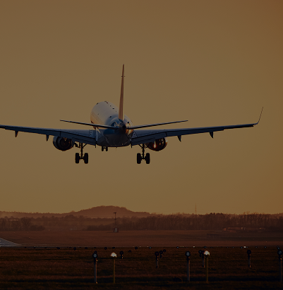 Avion en train d'atterrir sur une piste au coucher du soleil.