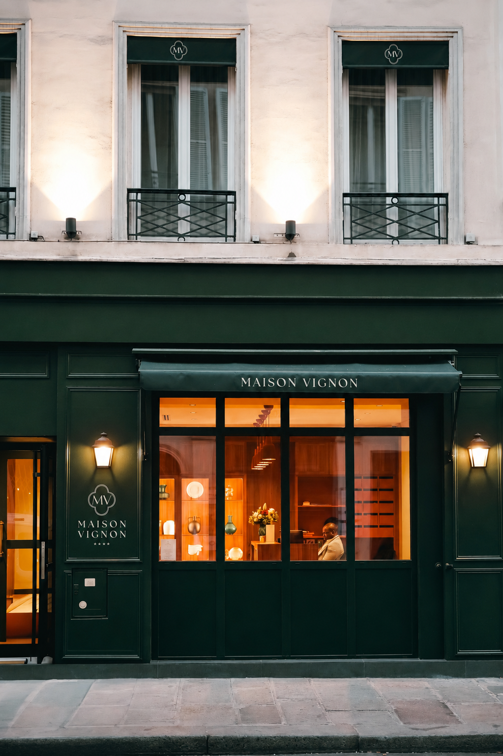 Façade verte foncée élégante d'une boutique avec enseigne Maison Vignon et une personne assise à l'intérieur.