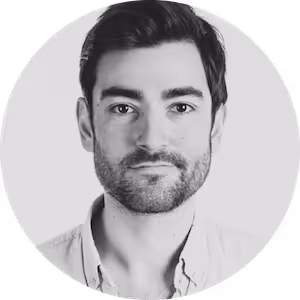 Black and white headshot of a man with short dark hair and a beard, wearing a light-colored shirt.