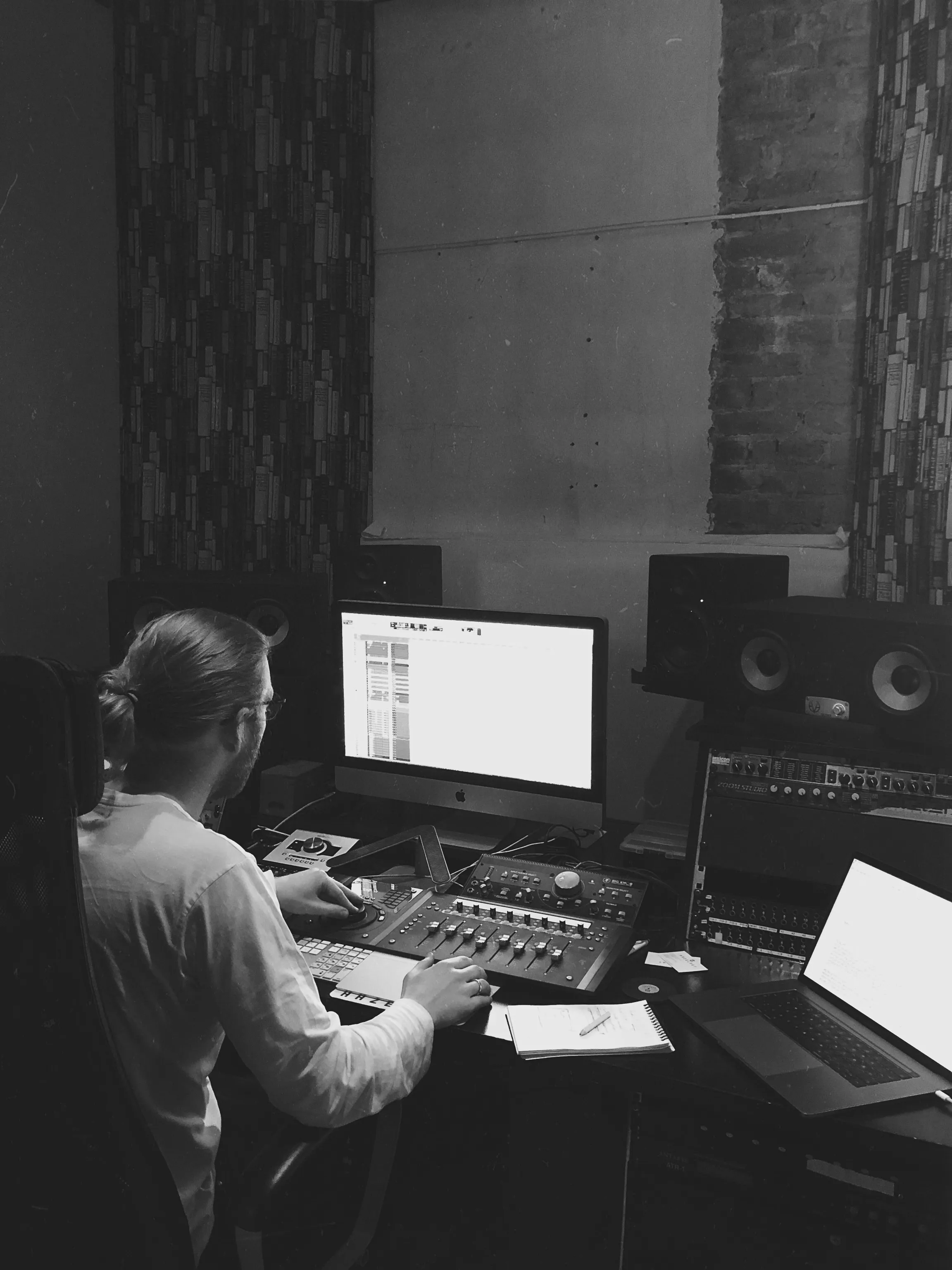 Person working on audio mixing equipment with computer screens in a recording studio.