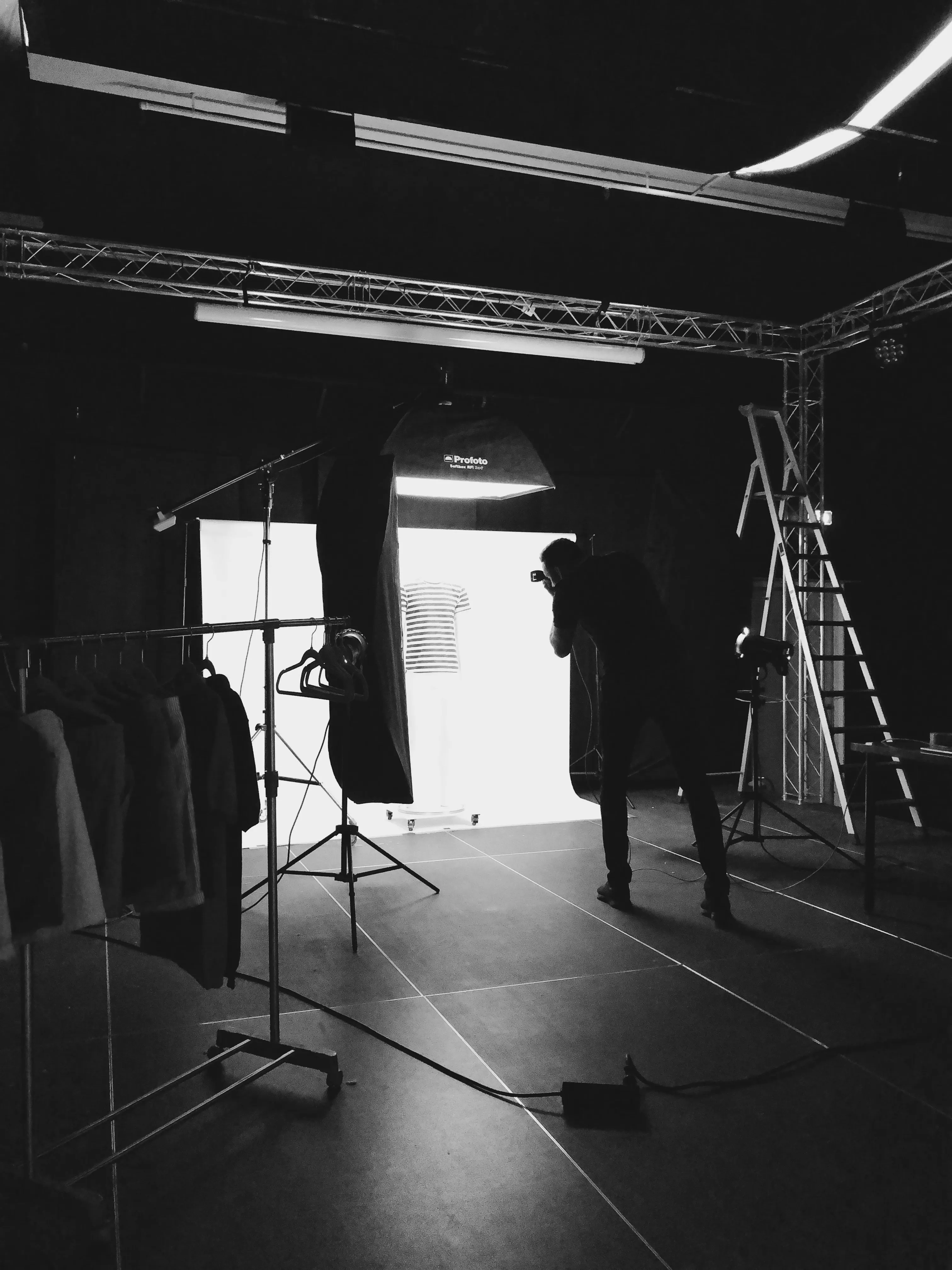 Fotograf tar bilder av stripete skjorte på klesmannequin i et mørkt studio.