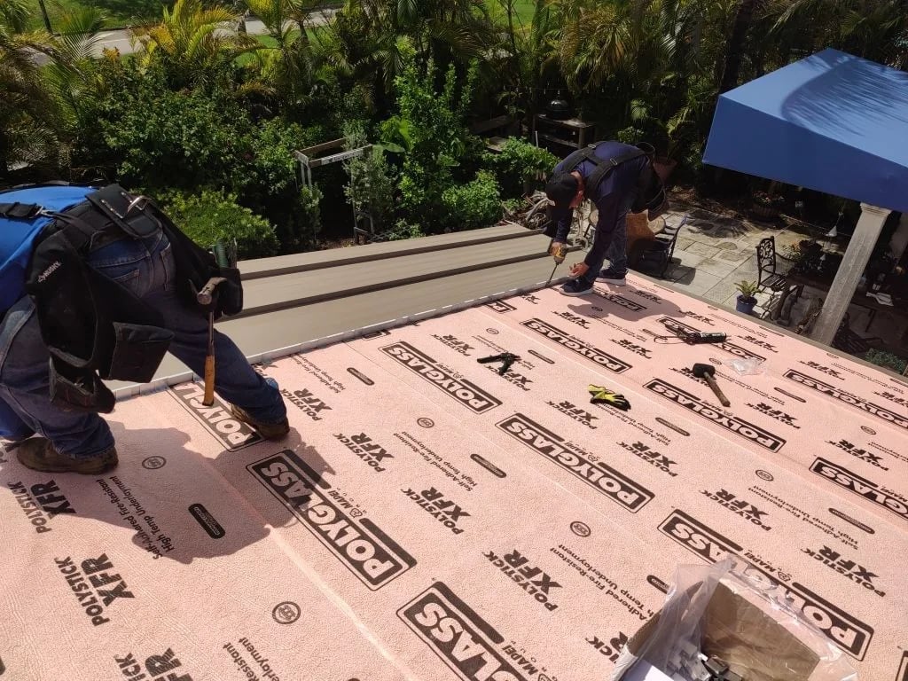 Roof repair technician inspecting storm damage on a Miami home