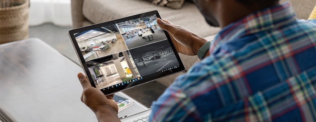 Man looking at CCTV screens on tablet