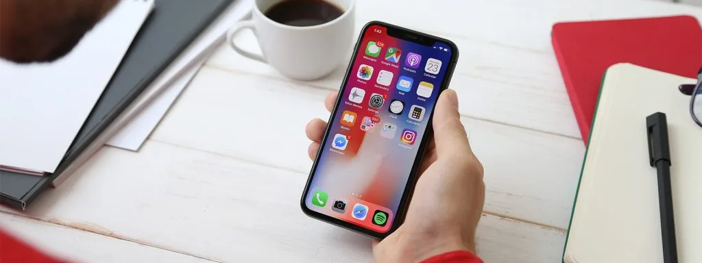 Business Mobile Plans. Man holding an iPhone, showing the apps on the home screen.