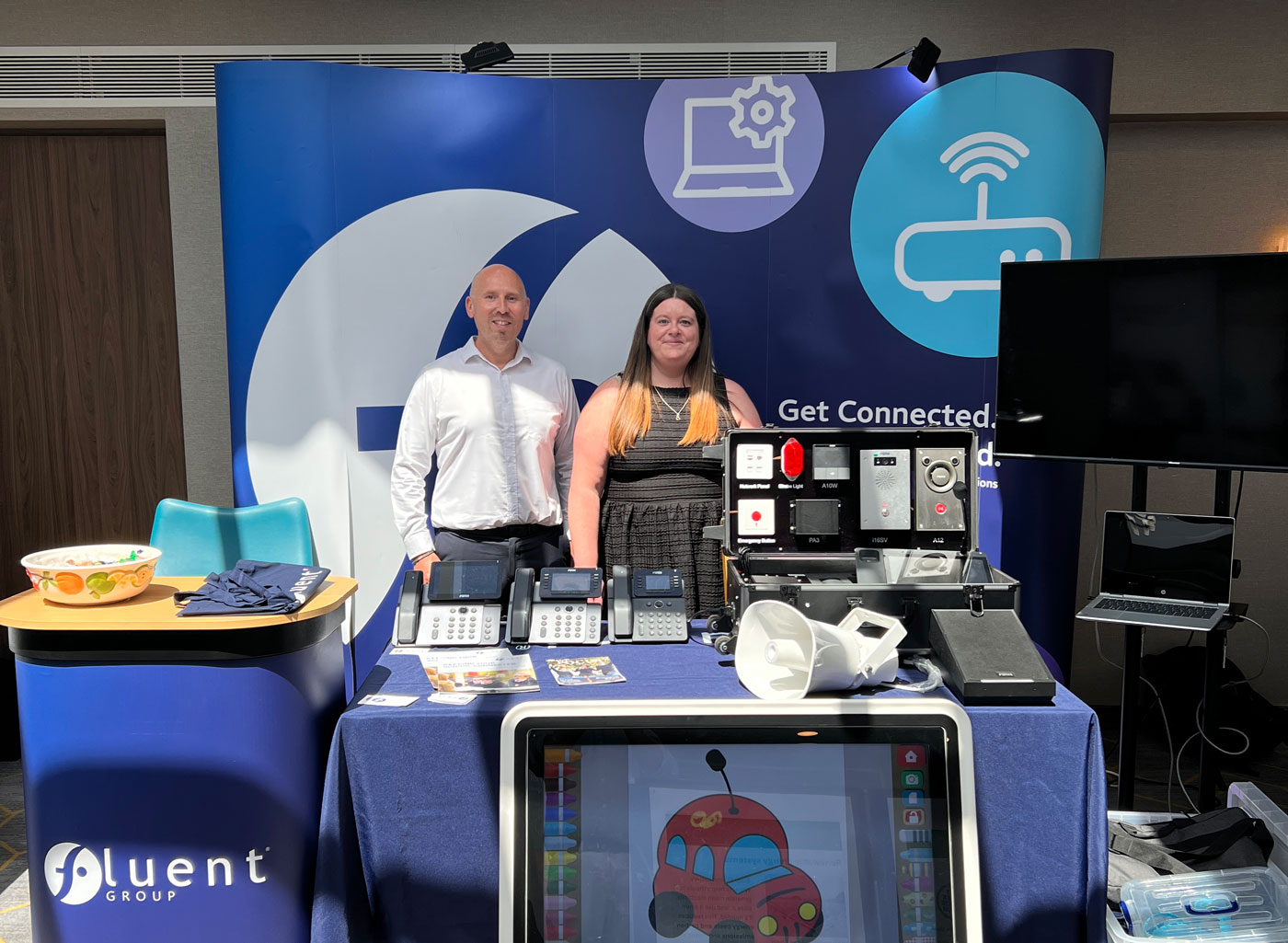 2 people stood behind a desk at an exhibition stand