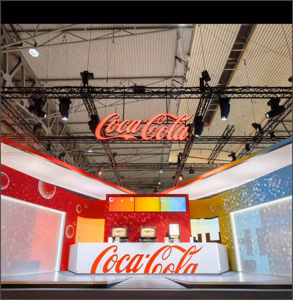 Coca-Cola exhibit booth with bright signage, soda dispensers, and colorful bubble-themed walls.